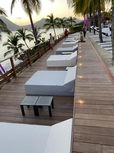 a row of white beds on a boardwalk next to the beach at Diamond rock in Le Diamant
