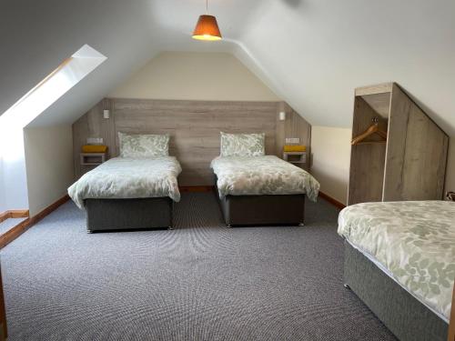 a attic bedroom with two beds and a sloped ceiling at Tavnaghoney Cottages in Cushendall