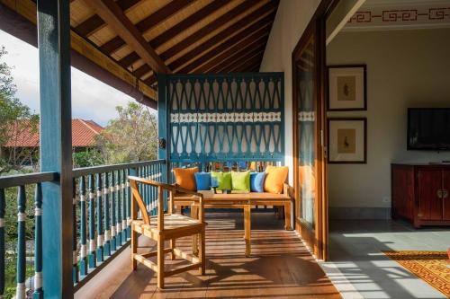 a porch with a bench with colorful pillows on it at Sudamala Resort, Sanur, Bali in Sanur