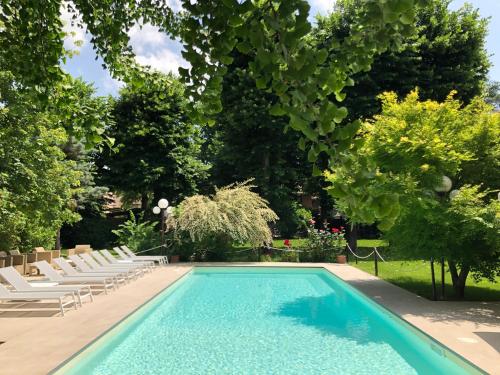 サリーチェ・テルメにあるHotel Milano Pool & Gardenの白い椅子と木々が備わるスイミングプール