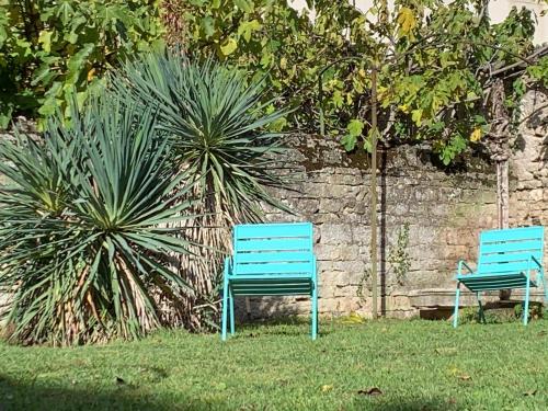 two blue benches sitting in the grass next to a wall at Les Tiercelines in Dole