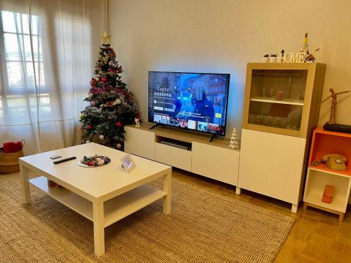 a living room with a christmas tree and a television at Villa Yoli, céntrico con plaza de garaje in Avilés