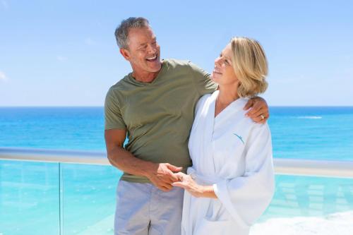 an older man and woman standing next to the ocean at Sun Palace - All Inclusive Adults Only in Cancún
