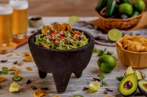 a bowl of guacamole on a table with chips at Sun Palace - All Inclusive Adults Only in Cancún