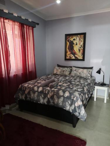 a bedroom with a bed and a red curtain at The Tree Of Idleness Guesthouse in Trafalgar