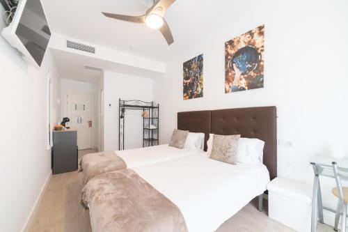 a white bedroom with a large bed and a ceiling fan at Hostal Puente de Hierro in Logroño