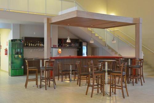 un restaurante con un bar con mesas y sillas de madera en Habitat Prime Hotel, en Leme