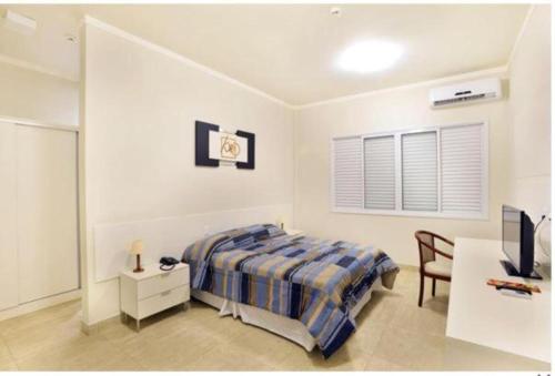 1 dormitorio con 1 cama, escritorio y TV en Habitat Prime Hotel, en Leme