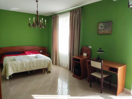 a bedroom with green walls and a bed and a desk at Casa Castellano in Nola
