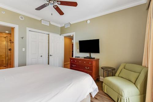 a bedroom with a bed and a chair and a television at Emerald Grande 922 in Destin