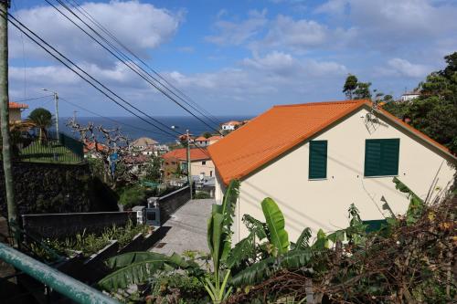a white house with an orange roof on a street at Casa das Feiteiras by AnaLodges in Ponta Delgada