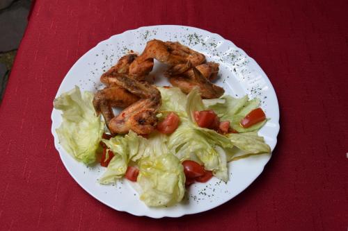 a plate of food with chicken lettuce and tomatoes at Penzión Príjemný Oddych in Banská Štiavnica