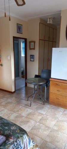 a living room with a table and a chair at Whispering Gardens in Stilbaai