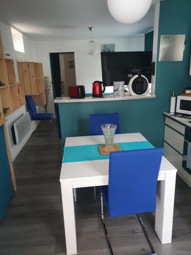 a kitchen with a white table and blue chairs at Maison individuelle avec jardin Sud Ardèche, Aubenas Vals les bains in Aubenas