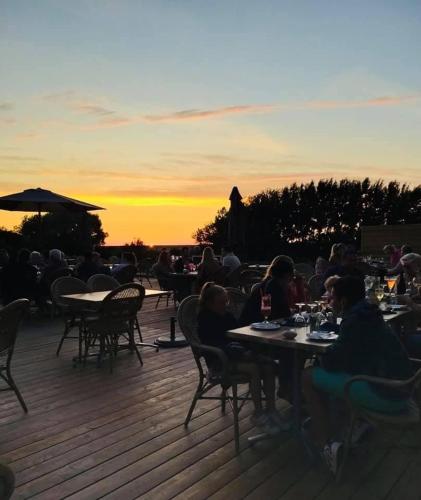 a group of people sitting at tables on a deck at sunset at Domaine de la Mer in Woignarue
