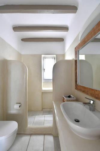 a bathroom with a sink and a toilet and a mirror at Orasea Villa with private pool in Parikia