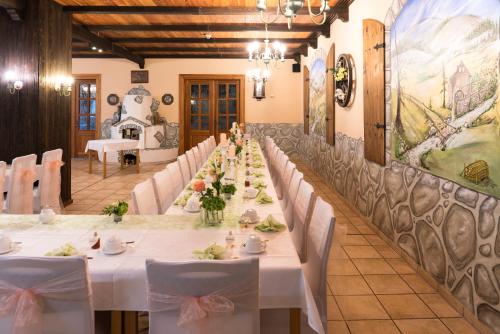 a long table in a room with white tables and chairs at Waldhotel Dietrichsmühle in Crottendorf