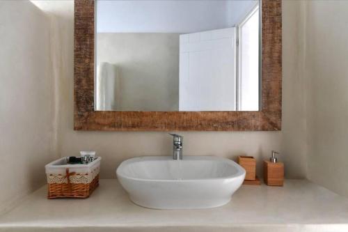 a bathroom with a white sink and a mirror at Orasea Villa with private pool in Parikia