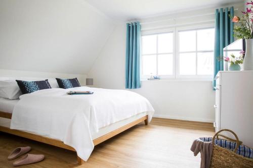 a bedroom with a white bed with blue curtains at Holiday house, Fuhlendorf in Fuhlendorf