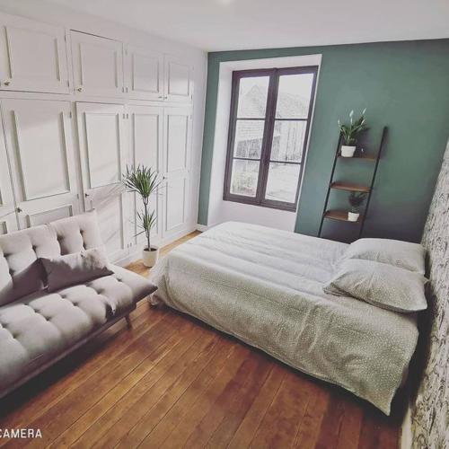 a bedroom with a large bed and a couch at Domaine de la Ferme de Jean Grogne in Fontenay-Trésigny