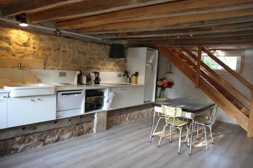 - une cuisine avec des placards blancs, une table et des chaises dans l'établissement Gite calme et cosy, toutes commodités et tourisme, à Vigny-lès-Paray