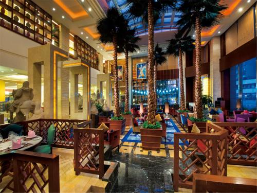 a hotel lobby with palm trees and tables at Chengdu Tianfu Sunshine Hotel in Chengdu