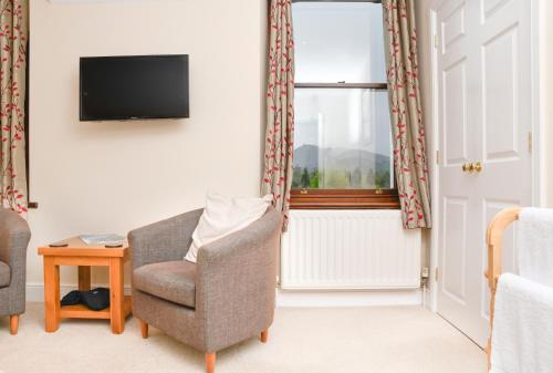 a living room with a chair and a tv and a window at West View in Keswick