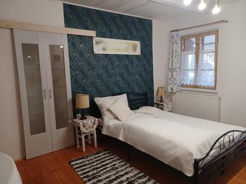 a bedroom with a bed and a blue wall at Magdolna Vendégház Magánszálláshely in Écs