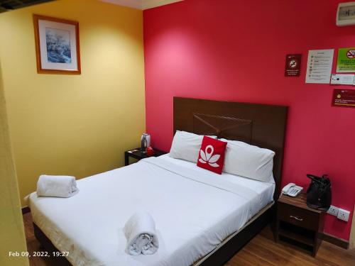 a bedroom with a white bed with a red wall at Hotel Sunjoy9 Bandar Sunway in Petaling Jaya