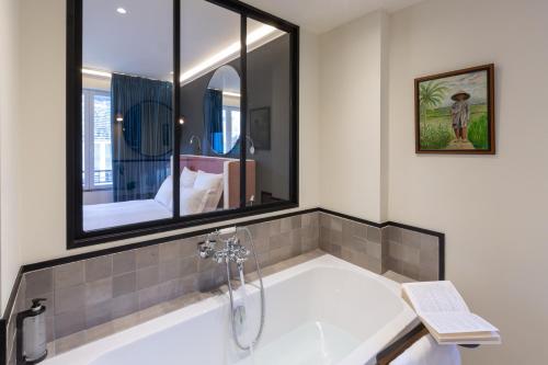 a bathroom with a bath tub with a mirror at Hôtel De Charme Le Chêne Vert in Brive-la-Gaillarde