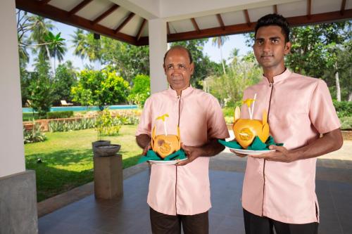 two men are holding up three bottles with plants in them at Anodawa Boutique Villa in Tangalle