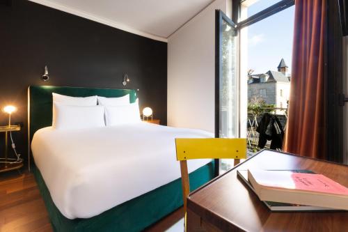 a bedroom with a bed and a desk and a window at Hôtel De Charme Le Chêne Vert in Brive-la-Gaillarde