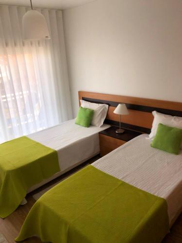 two beds in a hotel room with green sheets at Alojamentos Campo & Mar-T2 com Piscina in São Martinho do Porto