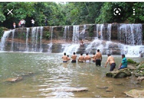 a group of men standing in the water near a waterfall at Hospedaje Independencia Pucallpa in Pucallpa