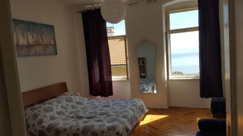 a bedroom with a bed and two large windows at Apartment Sandi in Rijeka