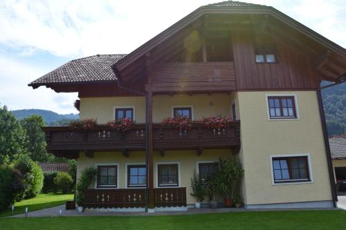 uma casa com uma varanda com flores em Appart Weisse Urlauben am Wolfgangsee em Sankt Gilgen