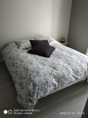 a bed with a black and white blanket and pillows at appartement avec terrasse in Aurillac