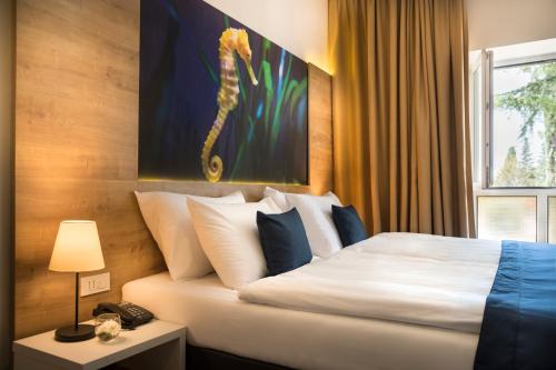 a hotel room with a bed and a picture of a seahorse at Remisens Hotel EPIDAURUS in Cavtat
