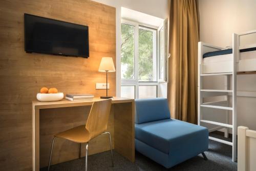 a room with a desk and a chair and bunk beds at Remisens Hotel EPIDAURUS in Cavtat