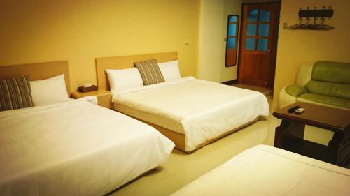 a hotel room with two beds and a chair at Camellia B&B in Taitung City