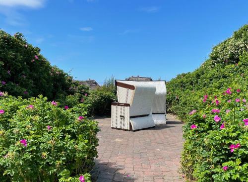 an old chair sitting on a brick walkway with flowers at Ferienwohnung Wattteufel in Rantum