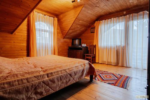 a bedroom with a bed and a tv and windows at Floarea Bucovinei in Vama