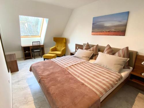 een slaapkamer met een groot bed en een gele stoel bij Lilie Appartement in Hévíz mit Tiefgarage, new and modern in Hévíz