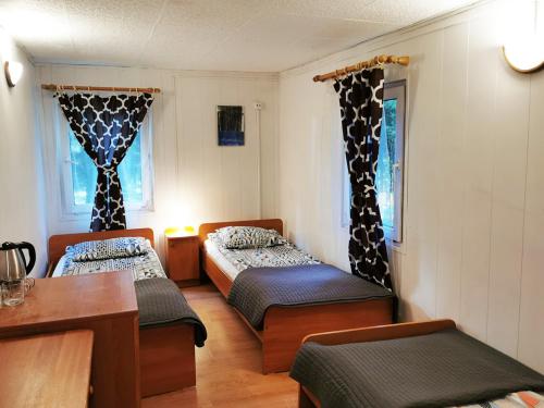 Pokój z 2 łóżkami i stołem oraz 2 oknami w obiekcie Nova Mazury w Świętej Lipce