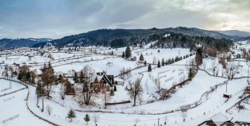 an aerial view of a snow covered mountain with a house at Floarea Bucovinei in Vama