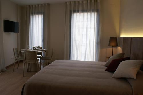 ein Hotelzimmer mit einem großen Bett und einem Tisch in der Unterkunft Aparthotel K in Figueres