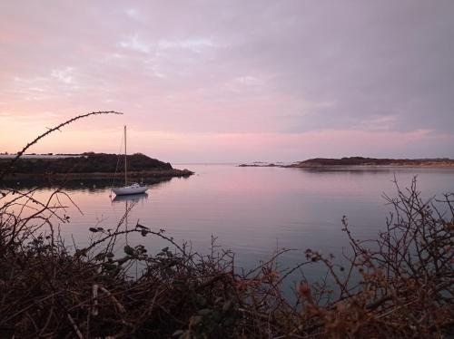 a sailboat sitting on a large body of water at Appartement dans gîte vue mer et campagne in Sibiril
