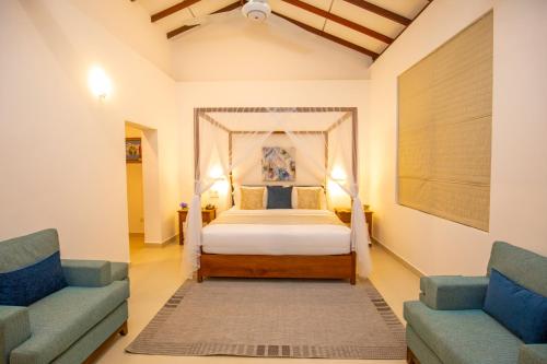 a bedroom with a bed and two blue chairs at Anodawa Boutique Villa in Tangalle