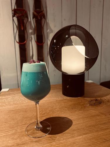 a blue drink in a glass on a table with a lamp at Hôtel 16 | 150 Montagne & Spa Nuxe in Vars
