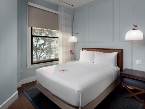 a bedroom with a large white bed and a window at Axiom Hotel in San Francisco